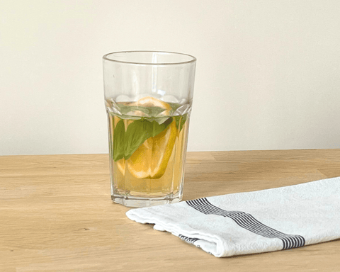 Verre de thé glacé maison pêche et basilic avec une rondelle de citron.